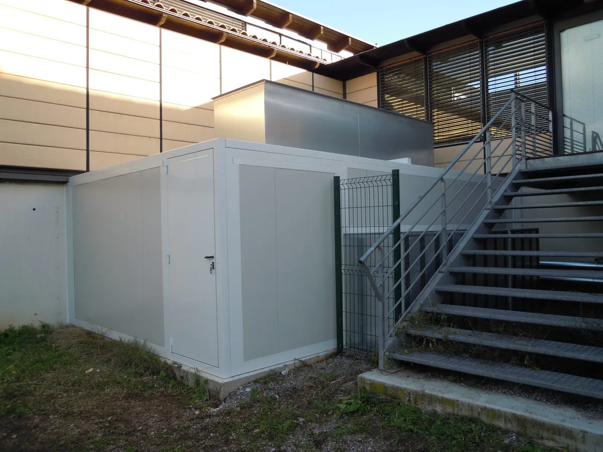 Capotage acoustique de pompe à chaleur installé au pied d'un bâtiment, à proximité immédiate des fenêtres et des riverains